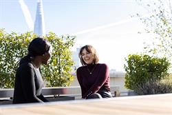 Two women talking outside with The Shard in the background