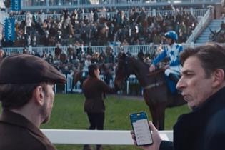 A still image from the Coral ad, showing two spectators next to a busy racecourse