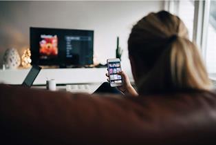 Woman looking at phone and digital TV