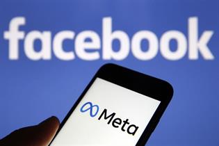 The Meta logo on a smartphone screen, with the Facebook logo in the background