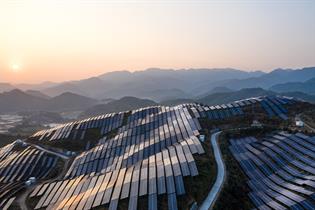 Aerial view of the solar power plant on the top of the mountain at sunset - stock photo