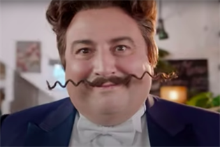 GoCompare's long-term brand mascot Gio Compario, with his zig-zagging, overlong waxed moustache, looks intensely into the camera, an unnerving smile playing on his lips