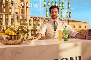 Bartender at an outdoor bar in Italy serving Peroni Nastro Azzurro 0.0% 