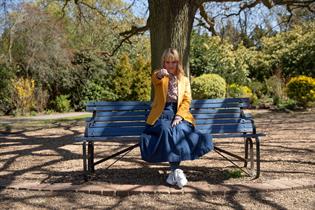 Photo of a woman sat on a bench with her fist out