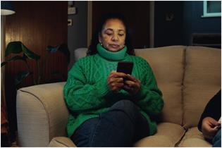 Woman sits on a sofa looking at her smartphone