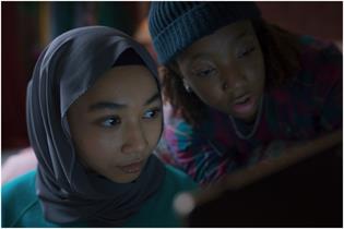 Two young people look intrigued while watching a laptop screen