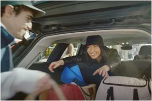 Man putting bags in the car boot with woman smiling in the back seat