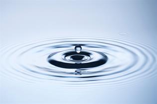 A drop of water causes ripples, disrupting a flat calm