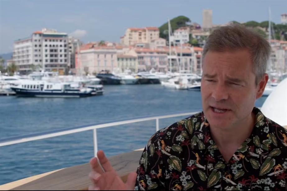 Alex Grieve sits talking on a yacht in Cannes harbour