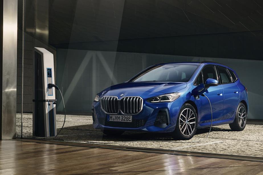 A blue BMW at an electric charging point inside a shiny metal room