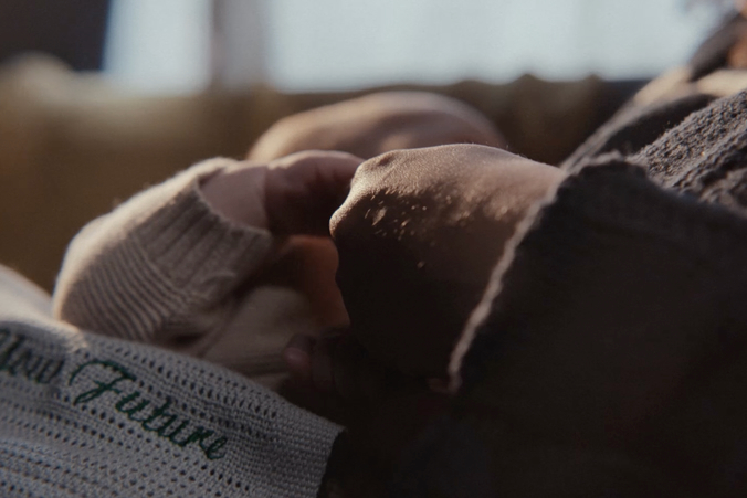 An adult's hand holds the small hand of a baby