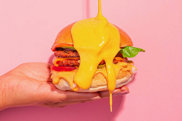 A burger in super-saturated colours, set against a luridly pink background