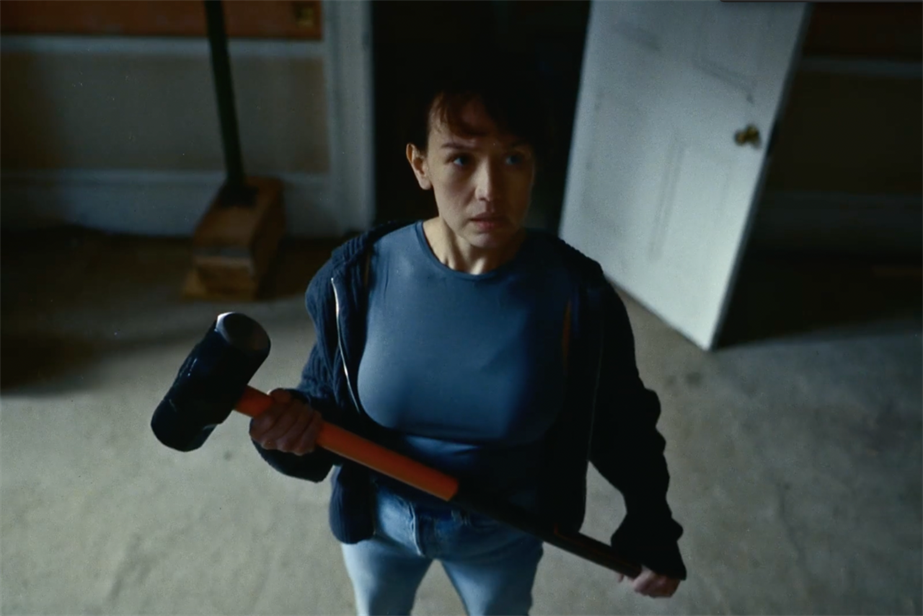 A woman stands with a sledgehammer 