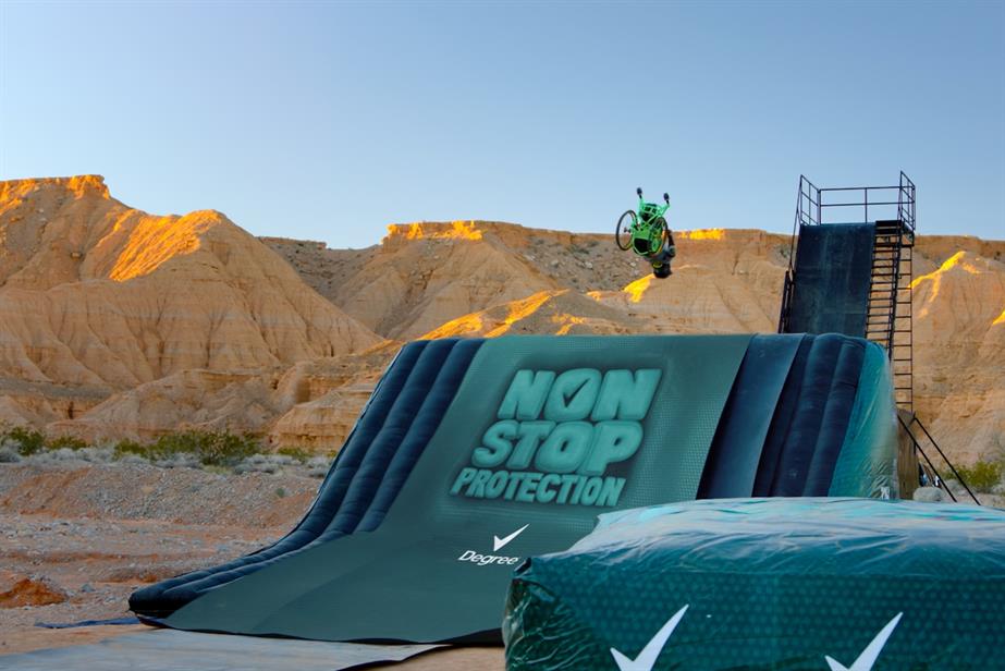A crash mat bearing Sure branding, over which Aaron 'Wheelz' Fotheringham performs wheelchair motorcross stunts