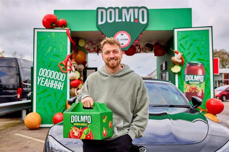 A man stands in front of the Dolmio Drive-Thru holding a box with the words Dolmio dinner bundle