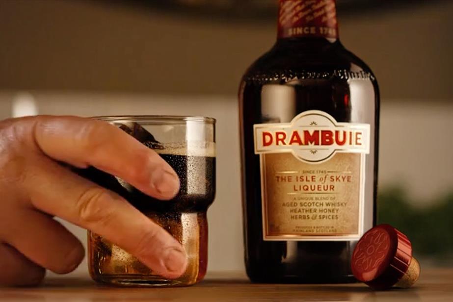 A picture of a glass in hand and a bottle full of Drambuie