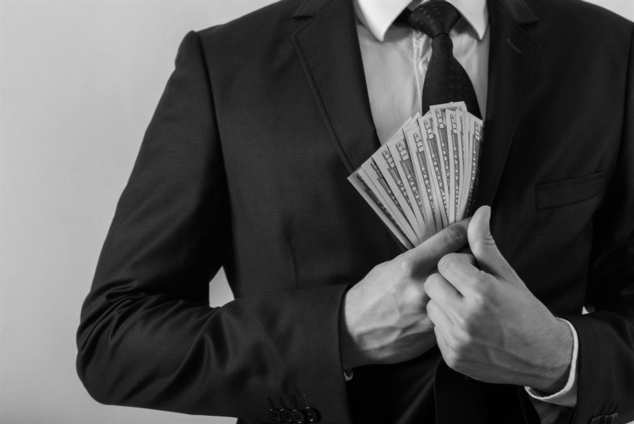A man in a suit pockets a wad of cash