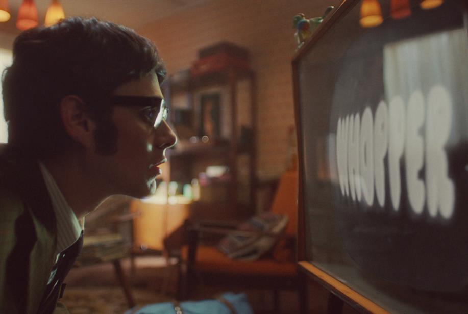 A man stares at his TV, where the word 'Whopper' appears onscreen