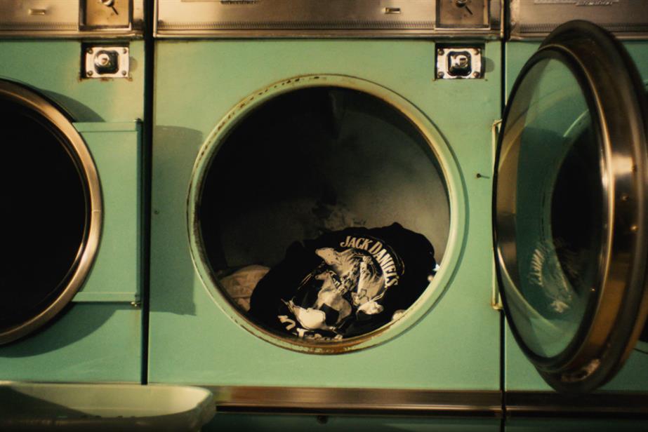 A washing machine in a launderette, inside it a Jack Daniel's t-shirt