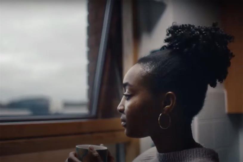 A woman looking out of the window while looking sad