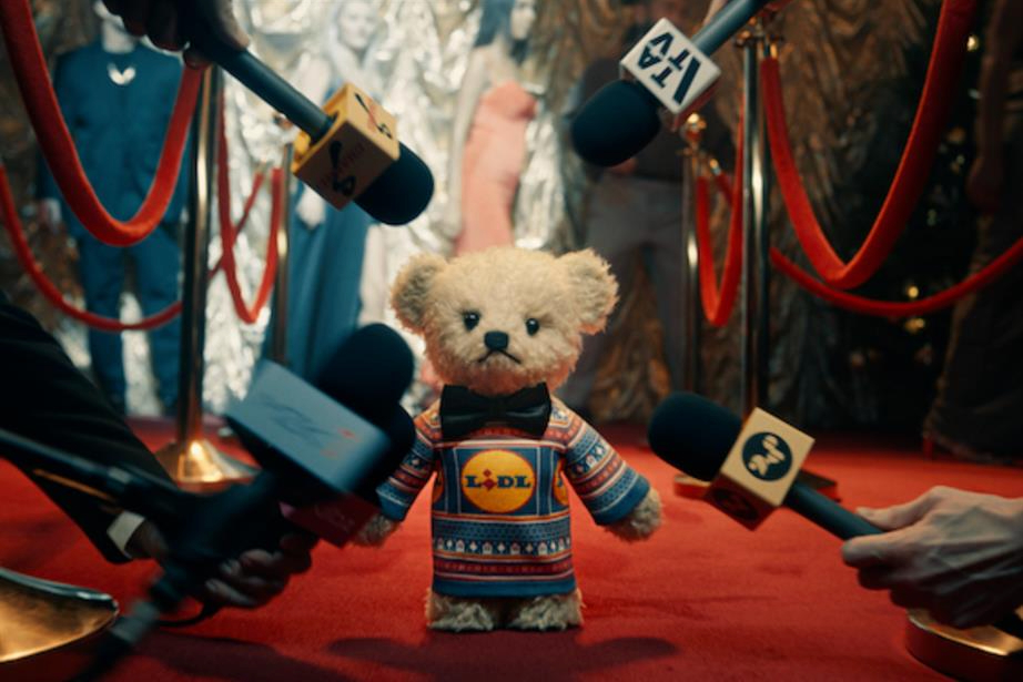A teddy bear being interviewed by wearing a Lidl Christmas jumper