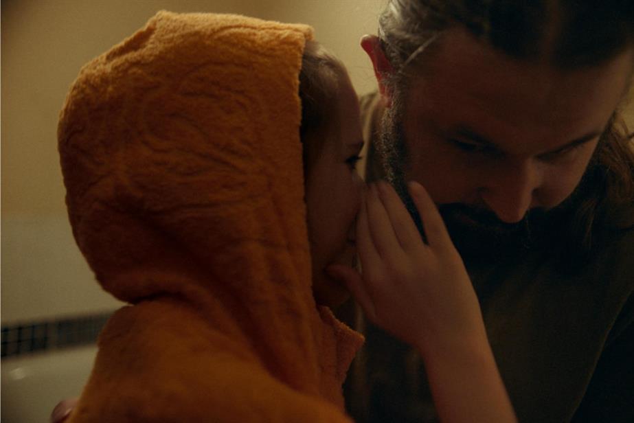 Daughter wearing orange hoodie whispering into her dad's ear