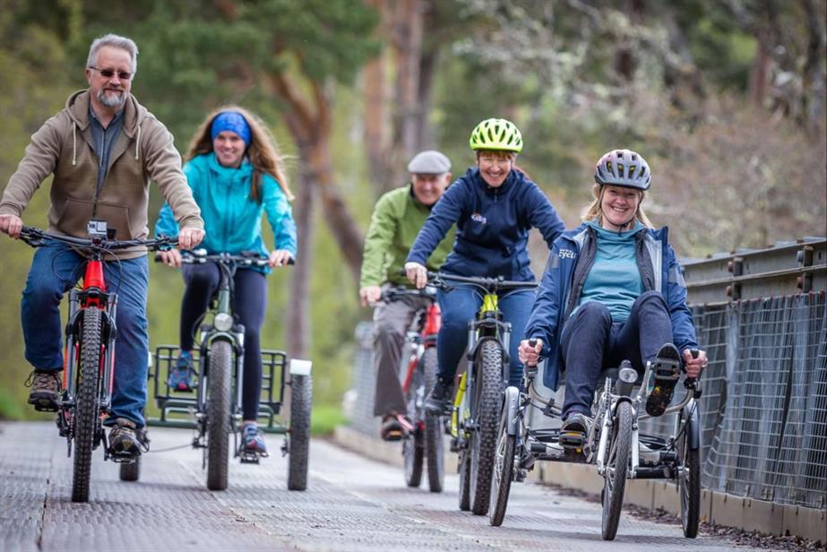Five people cycling over a bridge 