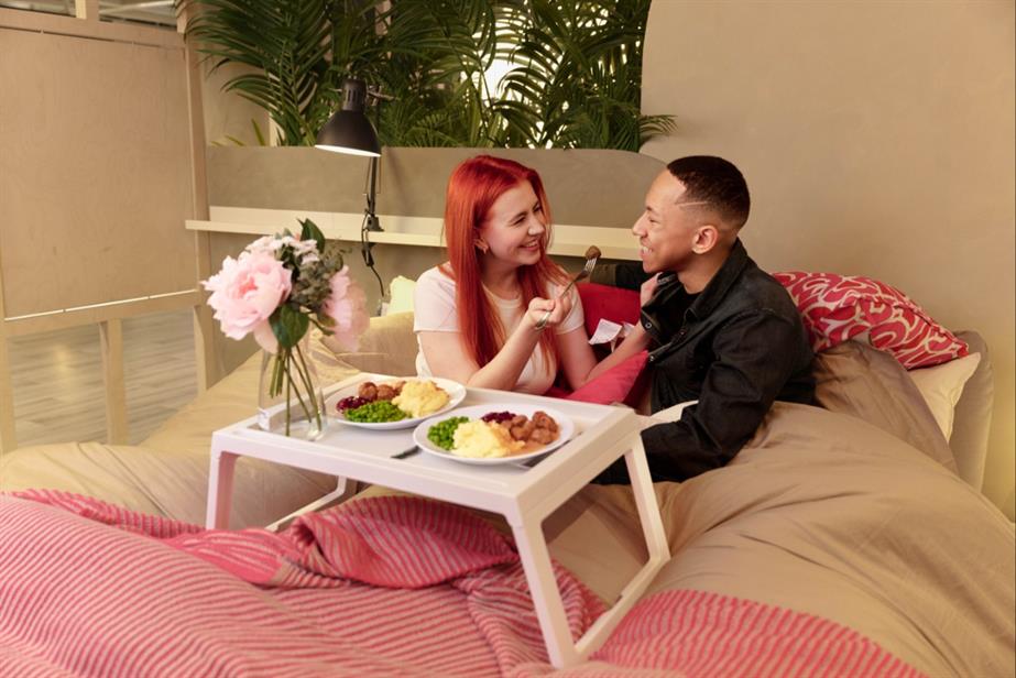 Couple in Ikea bed eating meatballs