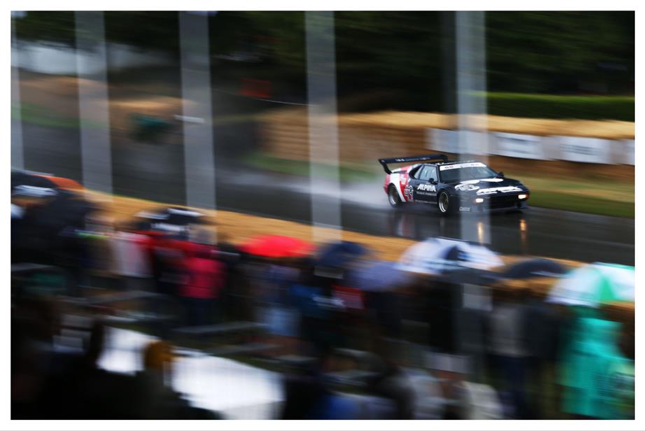 A race car driving on a rainy road