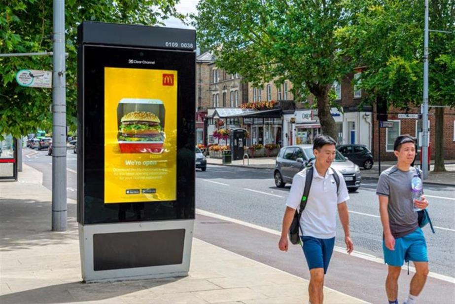 Clear Channel digital out of home board and two pedestrians