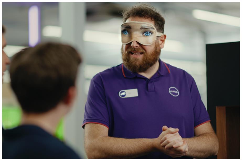 Man wearing an eye mask speaking to two people