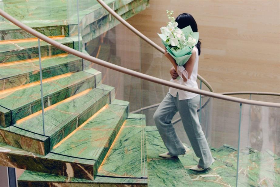  Mandarin Oriental Hotel Group - person walking up green marble stairs holding flowers