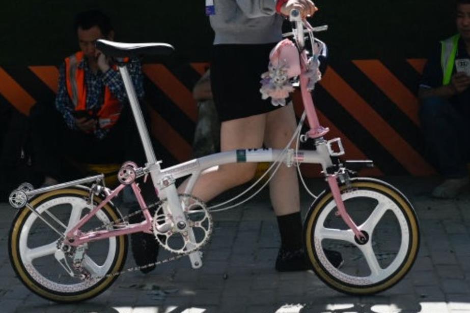 Woman walking with pink and white Brompton bike