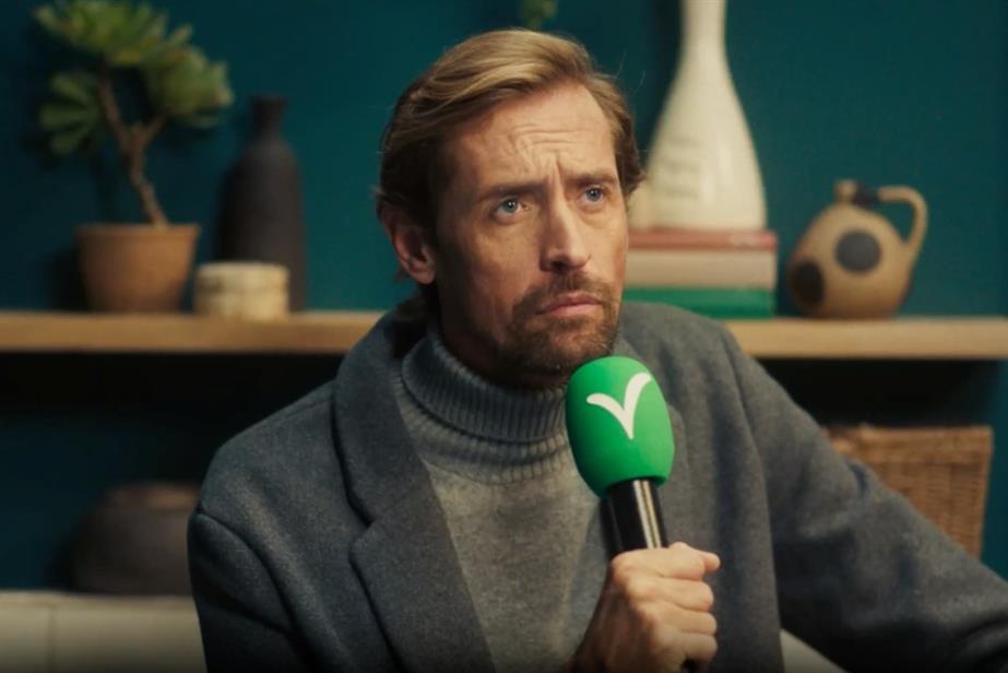 Peter Crouch holding a green microphone with Victorian Plumbing logo