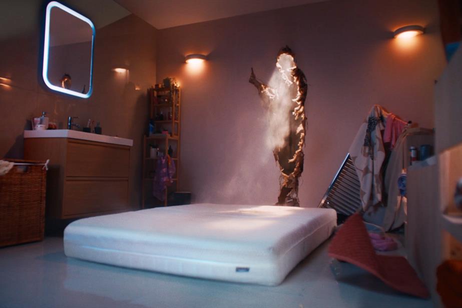 A mattress in lying on a bathrom floor next to a hole in the wall