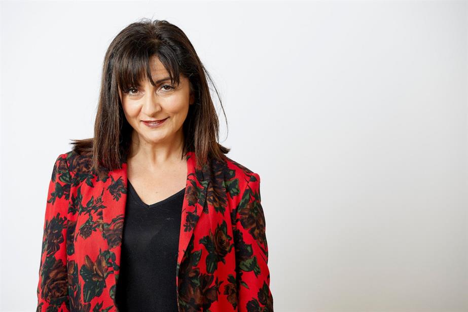 Photograph of Paula Joannou looking straight at the camera and wearing a black top and red and black jacket