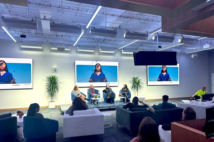 Four speakers on stage with audience watching