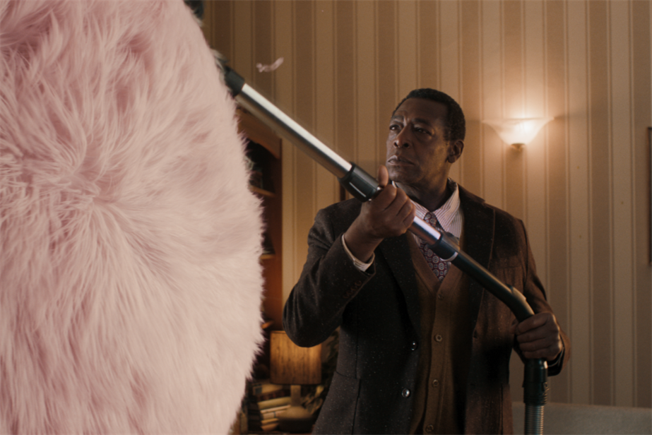 A man hoovering a giant ball of fluff