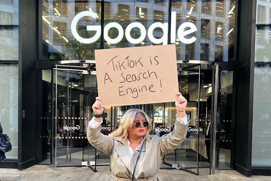 Woman holding sign saying 'TikTok is a search engine' outside Google office