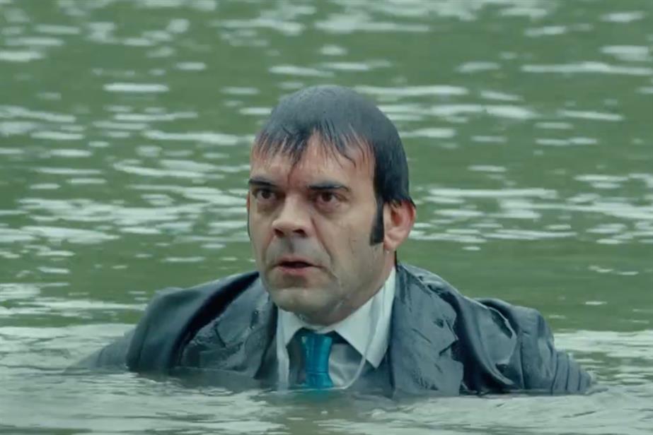 A man sits in a river, drenched.