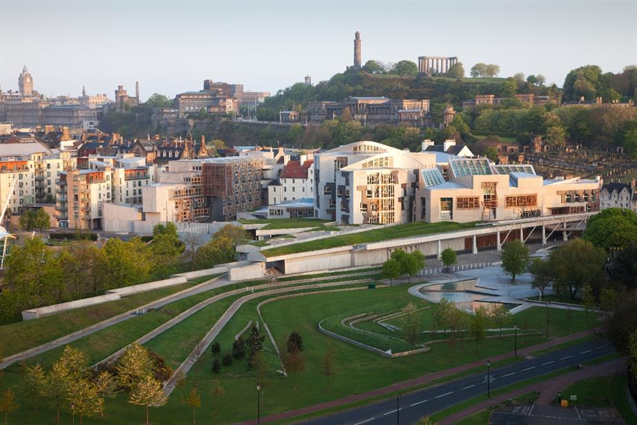 Morning light shining on Scottish Parliament in Edinburgh with Calton Hill in background.