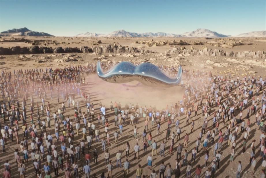 A gigantic silver moustache descends on a large crowd in a desert