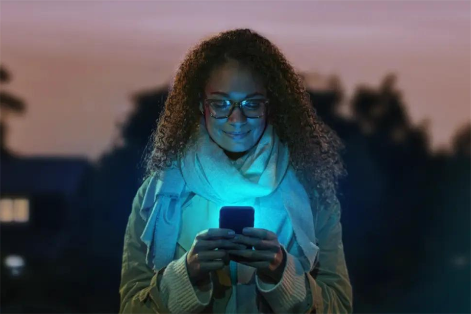 Image of woman holding smartphone emitting blue light