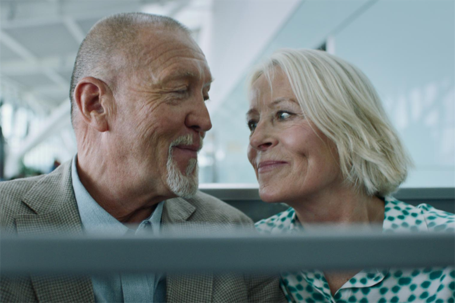 A man and his wife smiling at each other at Heathrow Airport