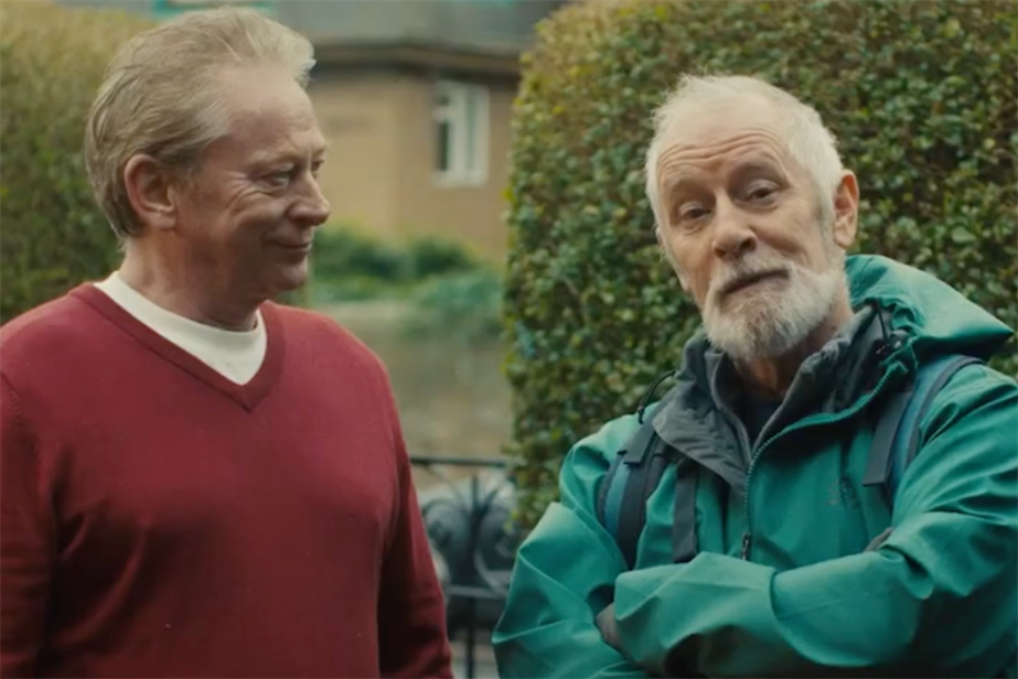 two men one wearing a red jumper and one a green coat 