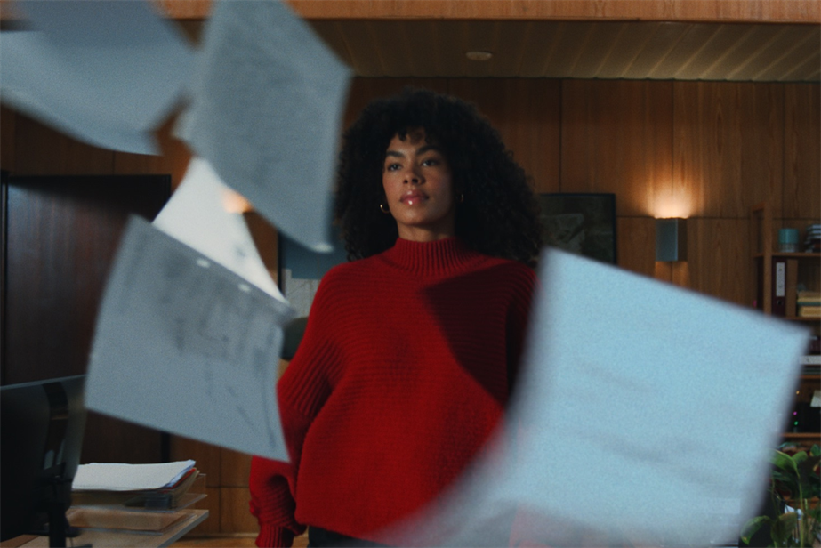 a woman wearing a red jumper walking through an office