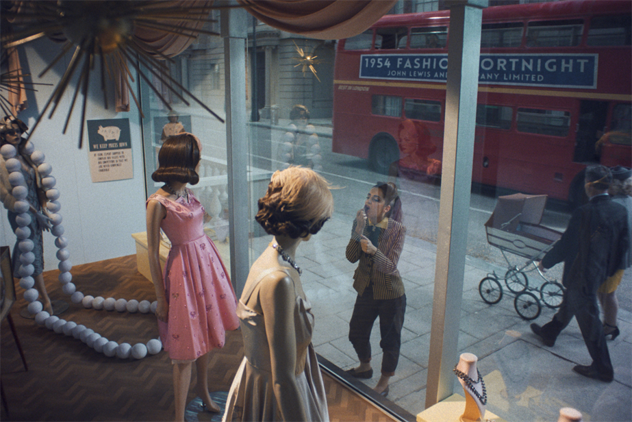 A woman looking at her own reflection in a John Lewis store window