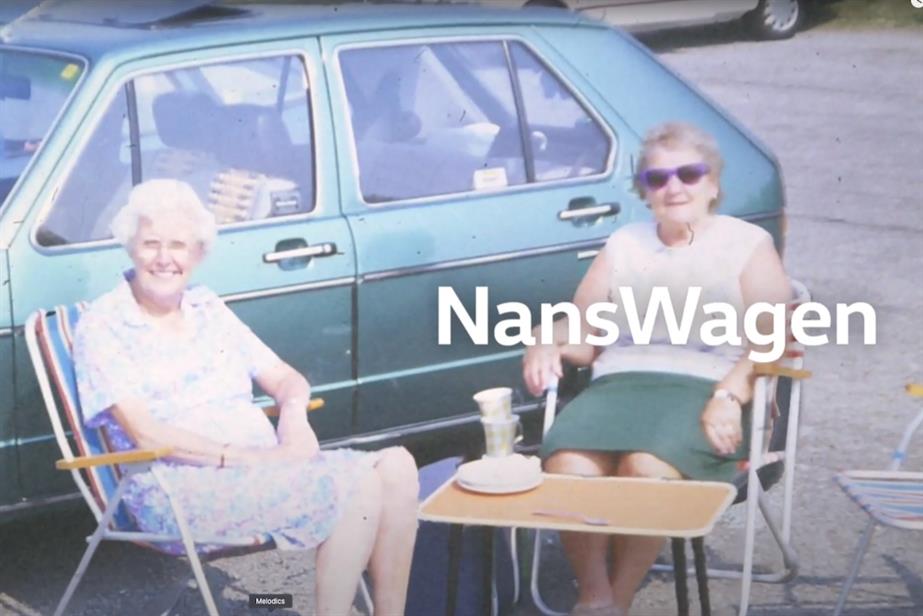 Two women sitting in chairs by a Volkswagen car