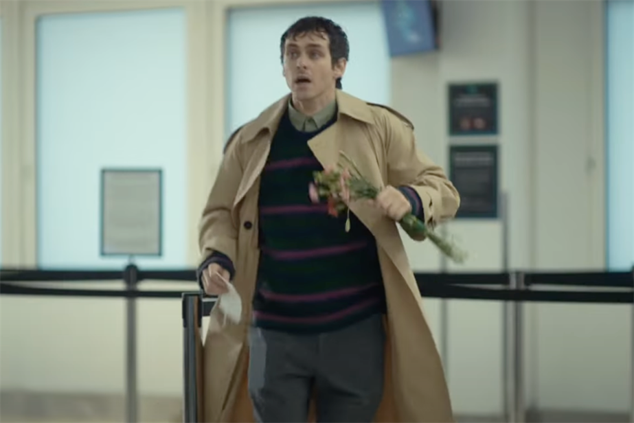 Man running through an airport holding flowers
