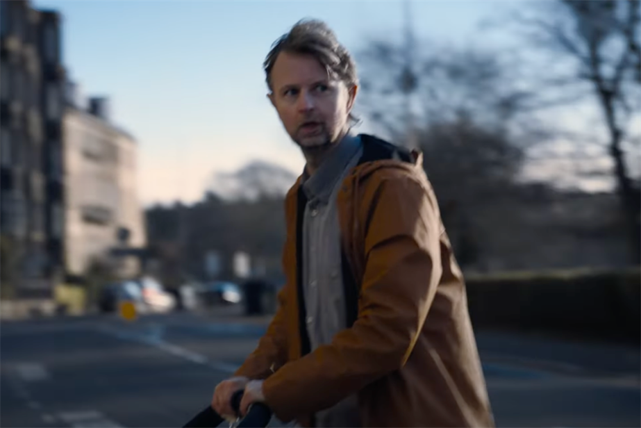 A man in a yellow coat crossing the road